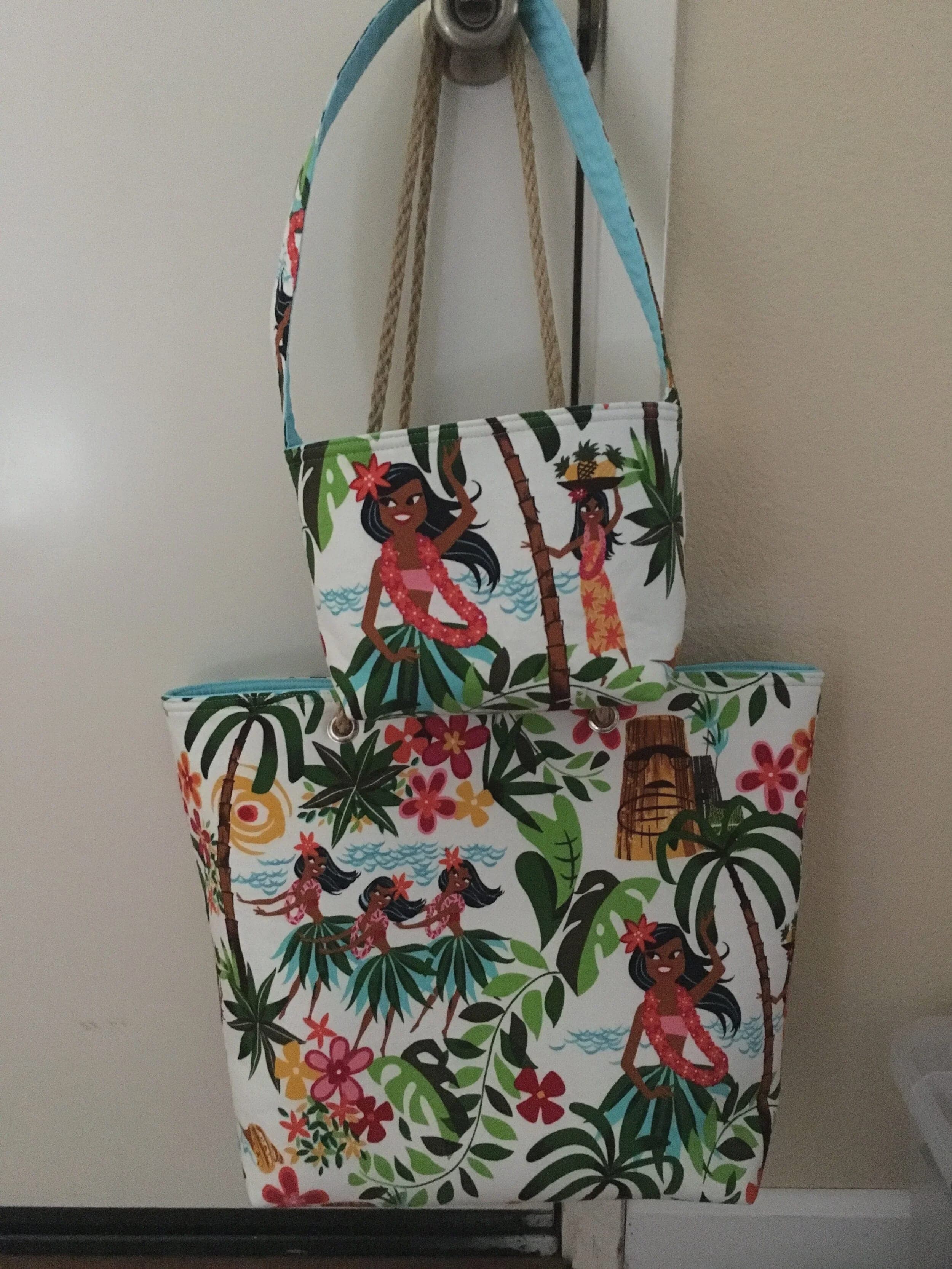Hula-print tote with rope handles hanging on a wall, a smaller matching tote in front of it