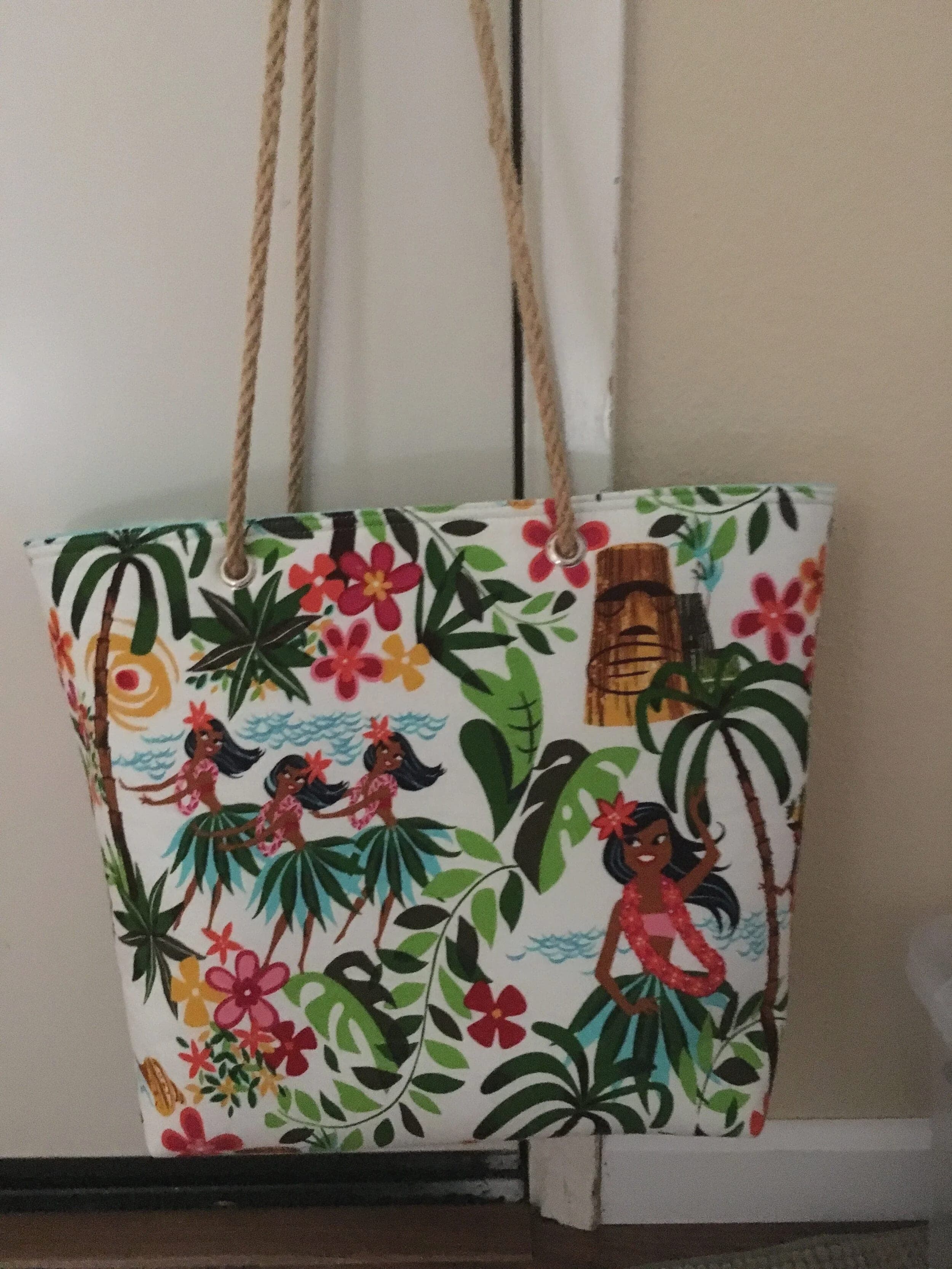 Hula-print cotton tote with rope handles, showing the tiki and palm pattern across the front