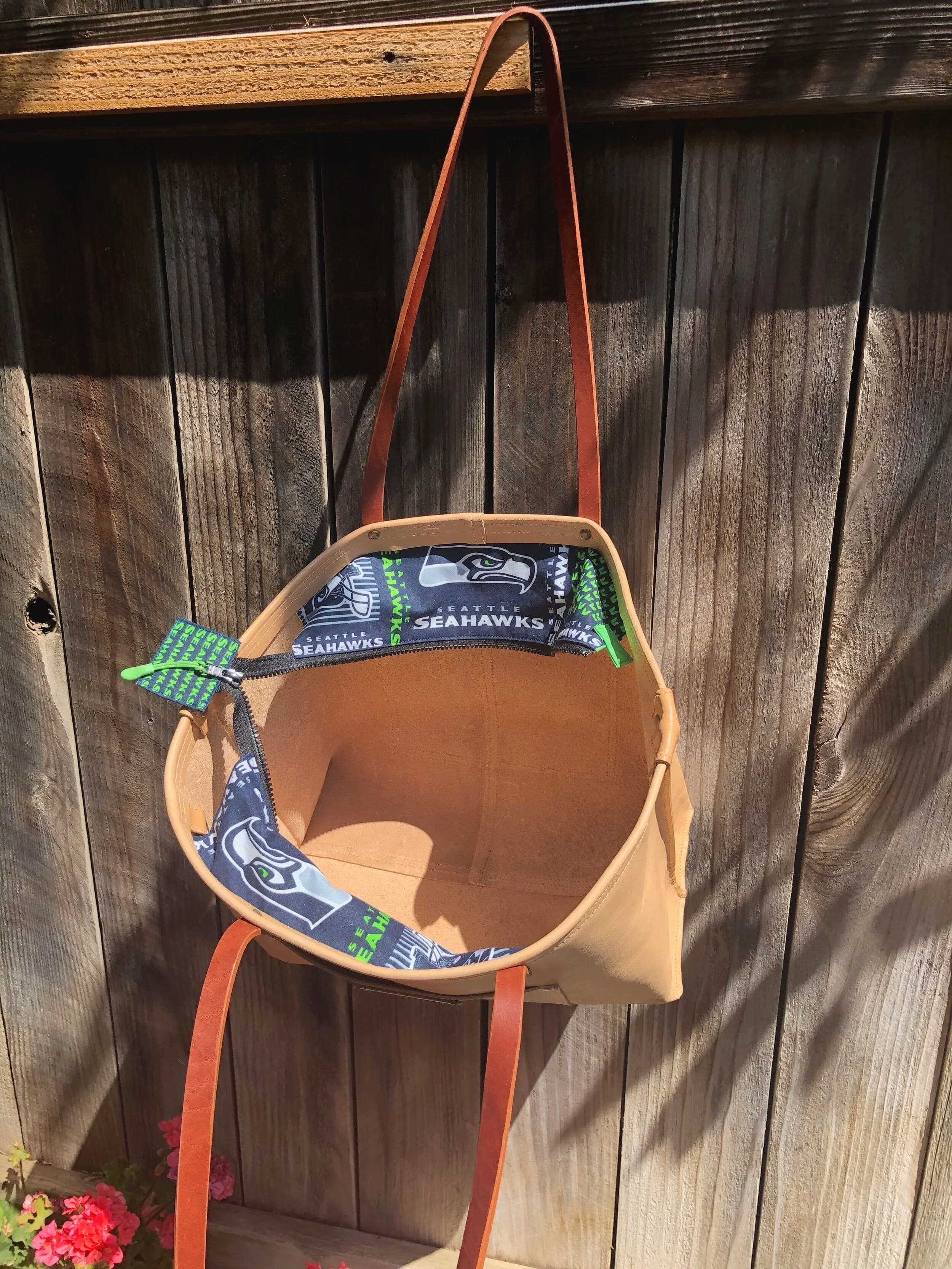 Natural tan leather tote held open to show the Seahawks-print lining and green tie