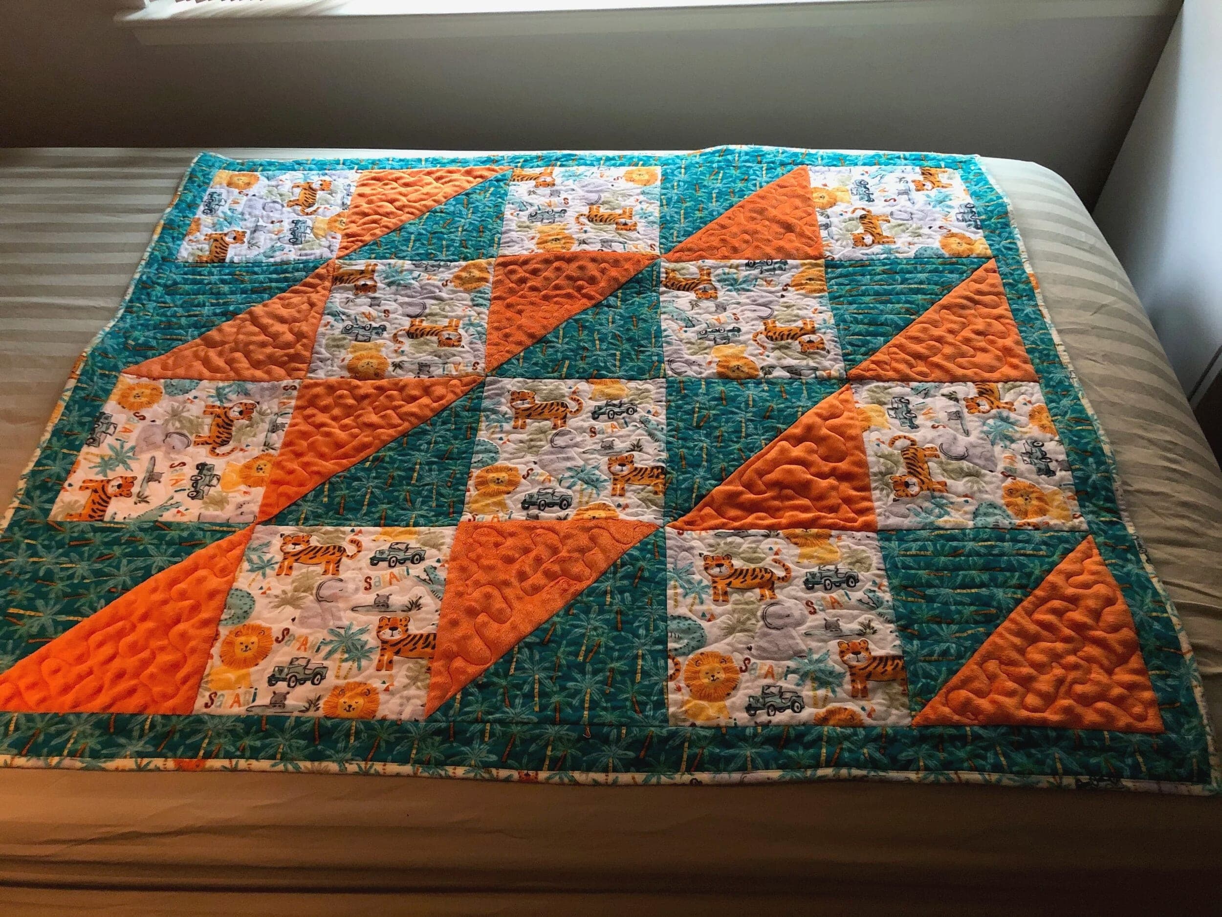 Orange and teal quilt with a novelty print, spread across a bed