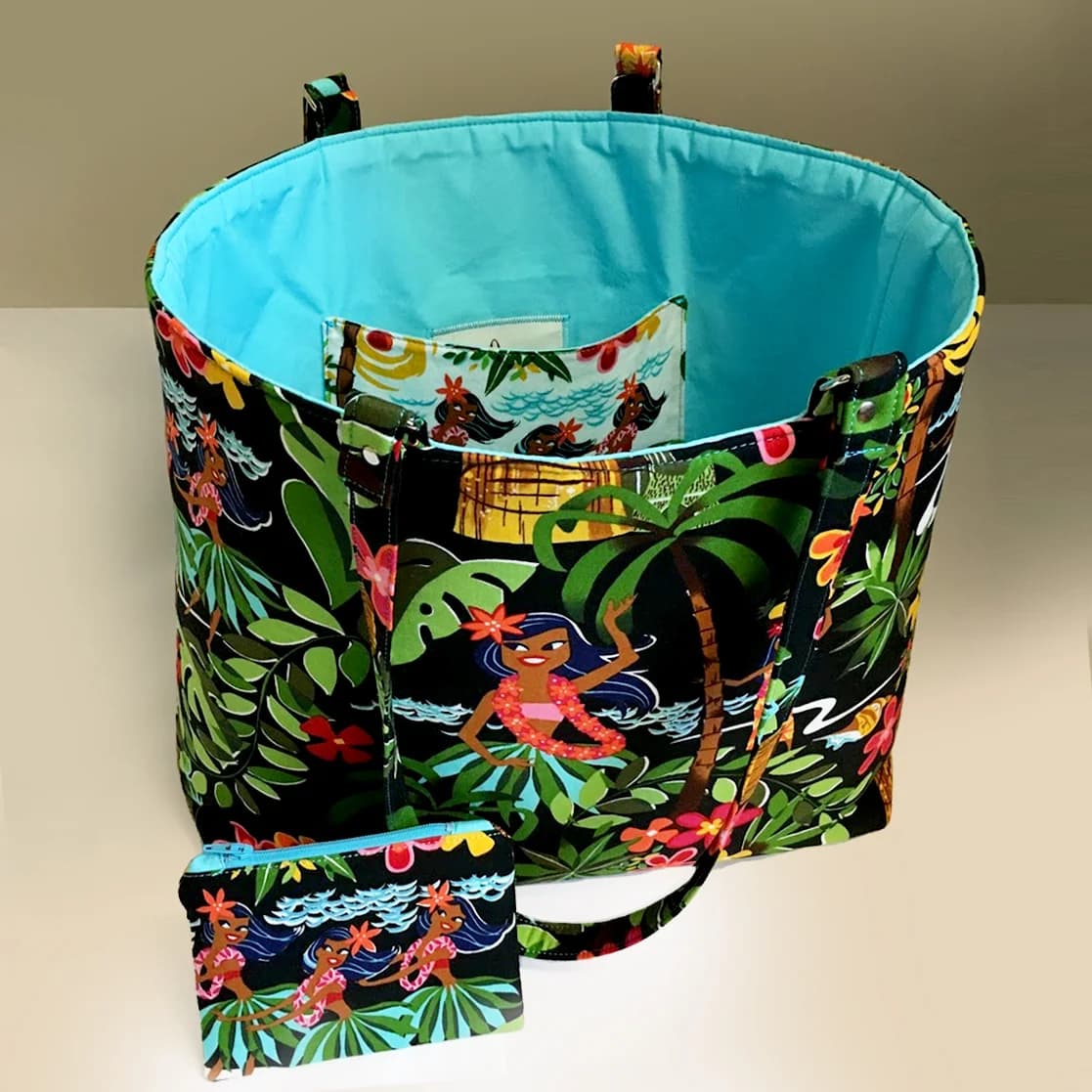 Cotton tote in a Hawaiian hula print, turquoise lining, standing open beside a matching zip pouch