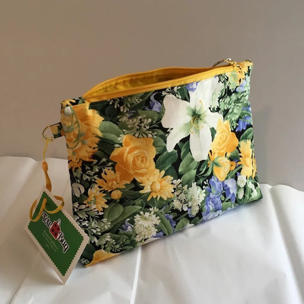 Zip pouch in a yellow and white floral cotton print with a yellow zipper and hang tag